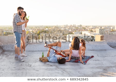 Stockfoto: Friends With Guitar Chilling On Picnic Blanket