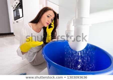 Foto d'archivio: Worried Woman Calling Plumber To Fix Sink Pipe Leakage