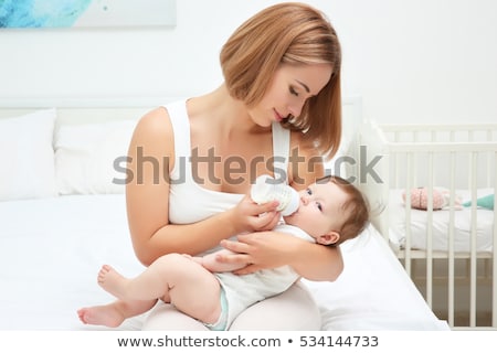 [[stock_photo]]: Woman Feeding Baby On Bed