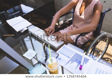 Сток-фото: Mid Section Of Young Disabled Mixed Race Businesswoman Working On Computer At Desk In The Office