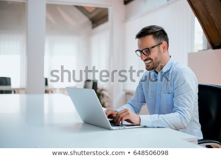 Foto stock: Portrait Of A Young Business Man Sitting By His Laptop In The Of