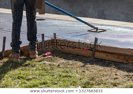 [[stock_photo]]: Construction Worker Smoothing Wet Cement With Long Handled Edger