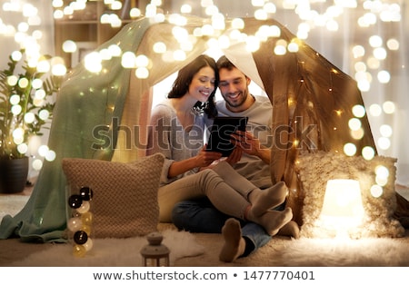 Stok fotoğraf: Happy Couple With Tablet Pc In Kids Tent At Home