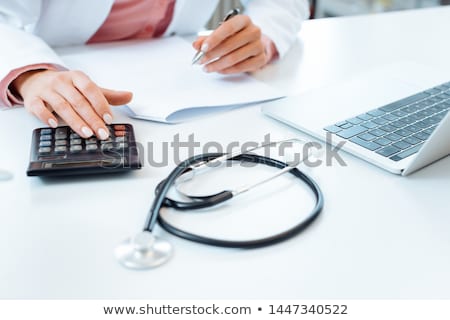 Foto d'archivio: Doctor Using Calculator Writing Bills And Doing Bookkeeping