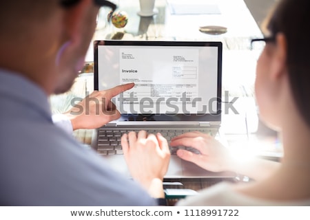 Stock photo: Two Businesspeople Checking Invoice On Computer