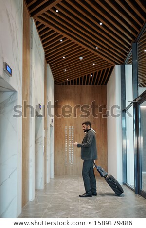 ストックフォト: Young Businessman With Suitcase Using Smartphone While Waiting For Elevator