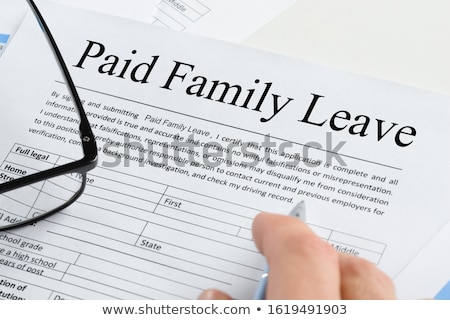 Foto stock: Hand Holding Pen Over Paid Family Leave Form