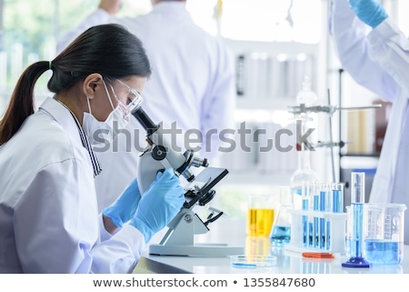 Stock fotó: Microscope And Green Chemical In Beaker In The Laboratory