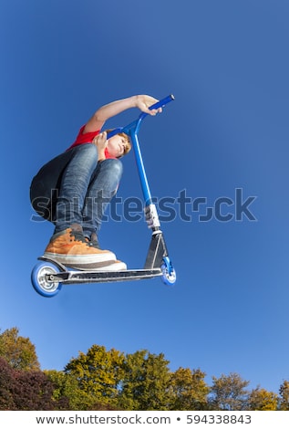 Stock photo: Boy Jumping With His Scooter At The Skate Park Under Blue Clear