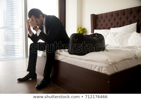 [[stock_photo]]: Lonely Businessman In Hotel Room Sitting On The Bed