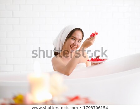 Foto stock: Smiling Woman Sitting And Looking At The Window In Bathtub