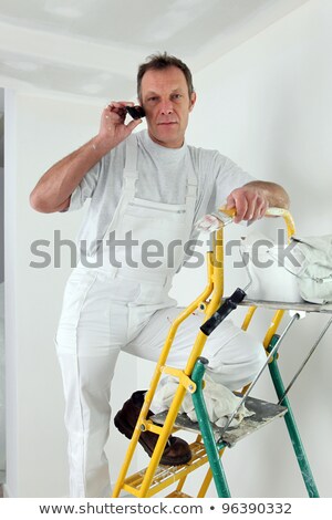 [[stock_photo]]: Painter Making A Call From Top Of Ladder