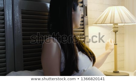 ストックフォト: Beautiful Young Woman Turning Off The Lamp