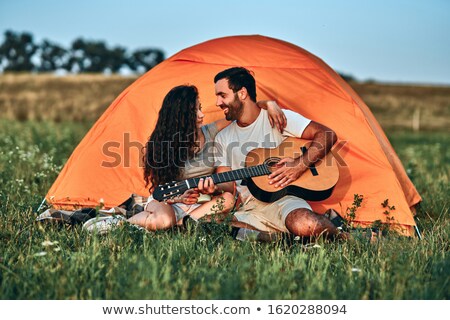 Сток-фото: Man Playing Guitar For His Girlfriend Sitting At The Tent