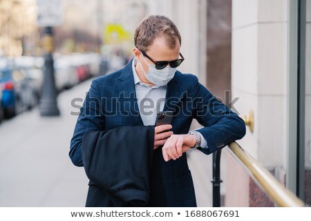 Stock foto: Busy Man Waits For Business Partner Looks At Watch Poses At Street Holds Modern Cellular Waits For