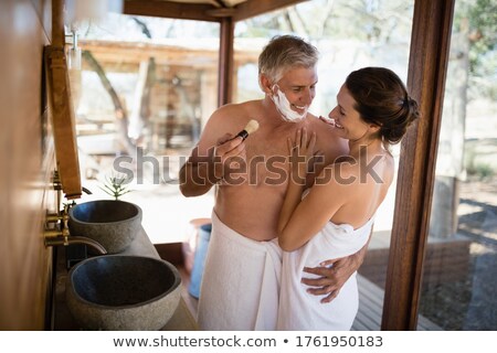 Foto d'archivio: Smiling Couple Looking Face To Face While Shaving In Cottage