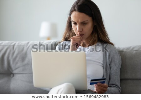 Foto stock: Serious Young Woman Holding Debit Card Using Laptop Computer