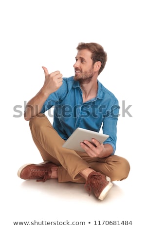 Foto stock: Seated Casual Man With Tablet Looks And Points Up