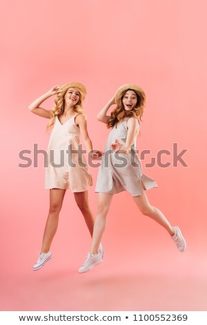 Foto stock: Full Length Of Two Pretty Young Girls Friends Jumping