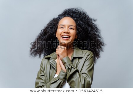 Foto stock: Overjoyed Dark Skinned Curly Woman Laughs Happily Laughs At Funny Joke Keeps Hands Pressed Togethe