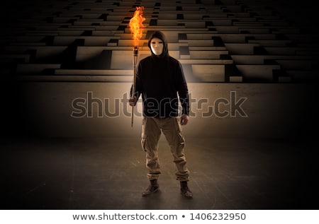 Stockfoto: Man Coming With Burning Flambeau From The Maze Concept