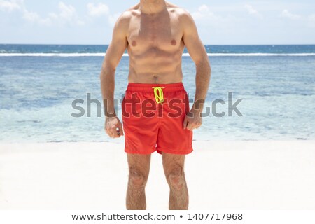 [[stock_photo]]: Shirtless Young Man In Red Shorts Standing In Front Of Sea