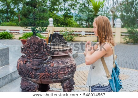 ストックフォト: Young Woman Traveler Praying In Polite Action With Incense Sticks At Buddhism Temple In Vietnam