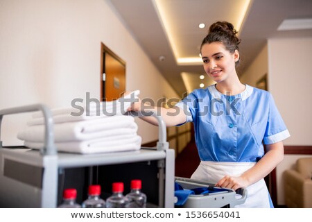 Zdjęcia stock: Young Smiling Chamber Maid Taking White Clean Towel From Top Of Stack