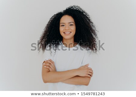 Foto stock: Portrait Of Young Pleasant Looking Woman With Curly Hair Keeps Hands Crossed Wears White T Shirt