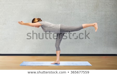 Foto stock: Woman Making Yoga Warrior Pose On Mat