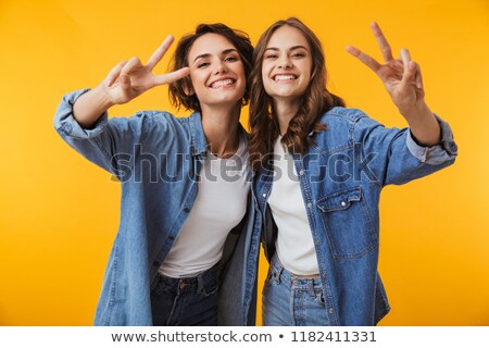 Zdjęcia stock: Emotional Young Women Friends Posing Isolated Over Yellow Background Showing Peace Gesture