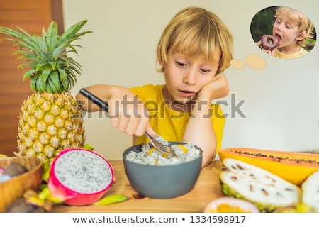 Stockfoto: Boy Eats Fruit But Dreams About Donuts Harmful And Healthy Food For Children Child Eating Healthy