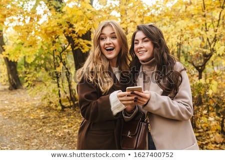 Zdjęcia stock: Two Cheerful Young Pretty Girls Wearing Coats Walking Together