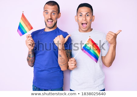 Foto d'archivio: Male Couple With Gay Pride Flags Showing Thumbs Up