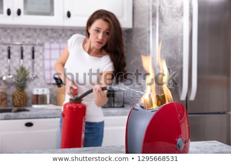 Сток-фото: An Afraid Woman Extinguishing Burning Red Toaster