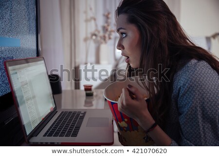 Foto stock: Shocked Wondered Woman Using Laptop And Eating Popcorn