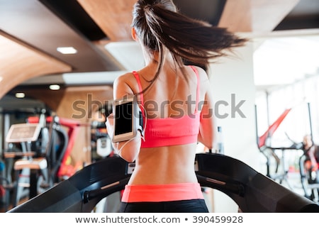 Stok fotoğraf: Woman Athlete With Balnk Screen Smartphone Running On Treadmill