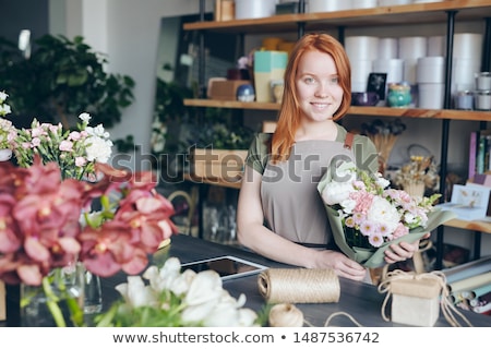 ストックフォト: Cheerful Beautiful Redhead Florist In Apron Standing At Table