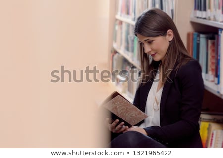 Сток-фото: Student Sitting Between Bookshelves Reading