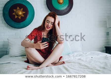 Stock photo: Smiling Redhead Woman Using Smartphone In Bed