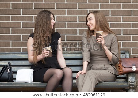 Zdjęcia stock: Two Attractive Women Holding Paper Cups Of Coffee And Chatting