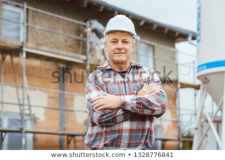 Zdjęcia stock: Proud Plasterer Standing In Front Of Scaffold On Construction Site