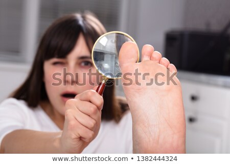[[stock_photo]]: Woman Looking At Her Toe Nails With Magnifying Glass