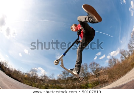 Сток-фото: Boy Jumps With Scooter At The Skate Park Over A Ramp