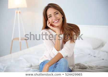 Foto d'archivio: Smiling Pretty Young Woman Sitting On Bed