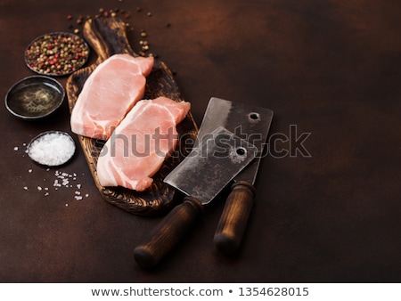 [[stock_photo]]: Raw Pork Loin Chops On Old Vintage Chopping Board With Knife And Fork On Rusty Background Salt And