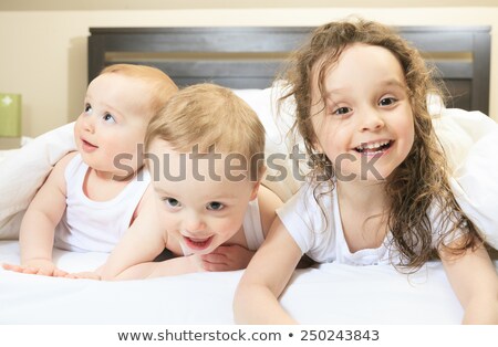 Сток-фото: Two Smiling Young Girls Lying On The White Bed