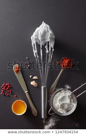 Sieve With Flour Spoon With Red Pepper A Metal Whisk And Halves Of A Boiled Egg On A Black Concret Сток-фото © artjazz