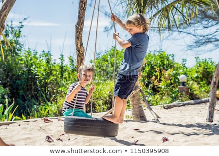 Stok fotoğraf: Two Little Blonde Boys Having Fun On The Swing On The Tropical Sandy Coast