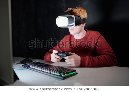 Stok fotoğraf: Young Man With Gamepad In Vr Headset Sitting In Front Of Computer Screen